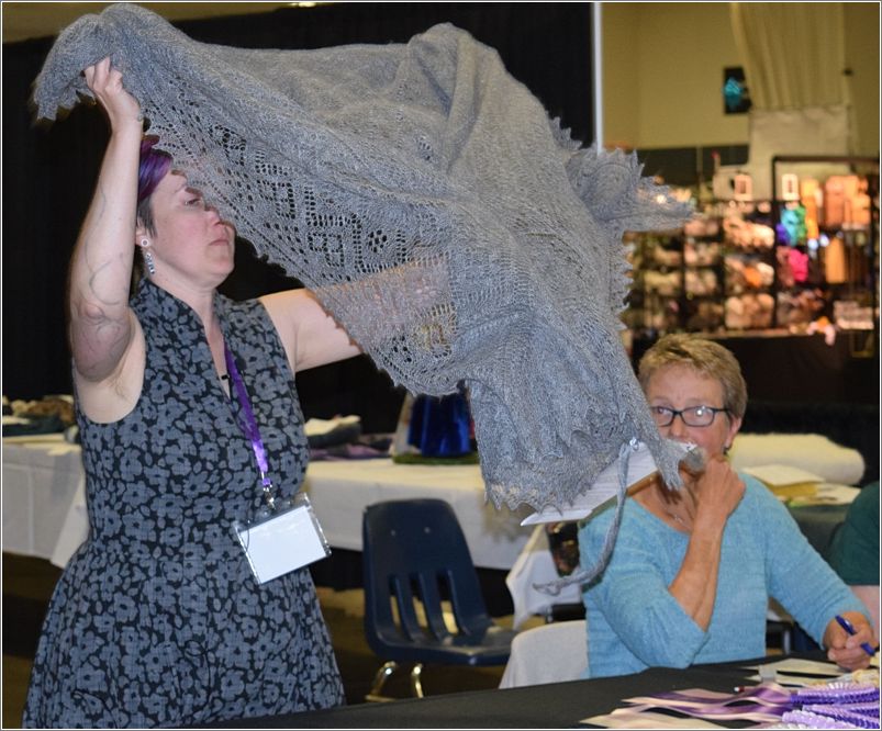 Judge Delaney shows Margo Siebenmorgans Reserve Champion Orenburg shawl. Photo: Peggy Lundquist.